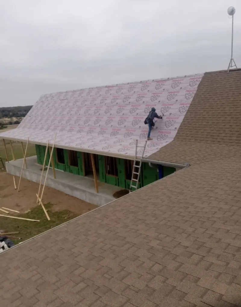 Worker preparing underlayment for a metal roof installation in South Gate Ridge